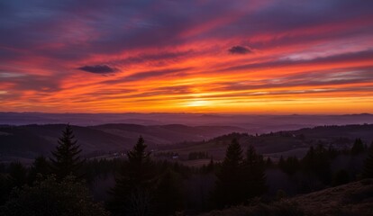 Fototapeta premium Fiery sunset over rolling hills dotted with trees; a landscape photo.