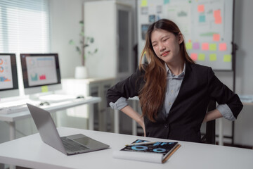 Asian office worker feeling backache after long hours of using laptop computer, incorrect posture...