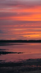 Fototapeta premium Sunset over calm water with silhouetted landscape