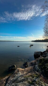A sunny clear day without wind on a rocky lake shore near Stora Sundby slott, Sweden
