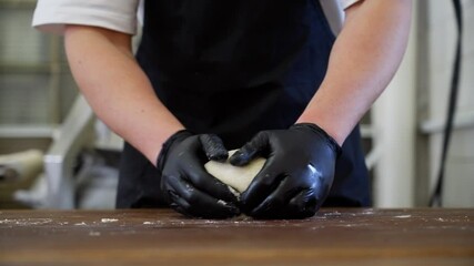 Kneading dough and shaping loaves of bread from it by a professional baker. The process of preparing delicious pastries in a bakery. High quality 4k footage