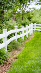 White fence curves along green lawn, lush trees background; idyllic property image
