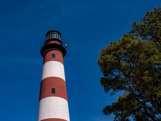 The red and white striped Assatageue Island Lighthouse on the Virginia Coast on a beautiful blue sky spring day