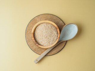 Psyllium husk in the plate with spoon on yellow background.