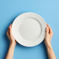 Hands holding an empty plate against a blue background in a minimalist setting