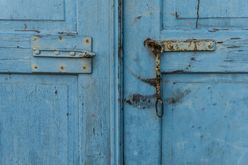 Weathered blue wooden door with rusty hardware and chain lock in a rustic setting