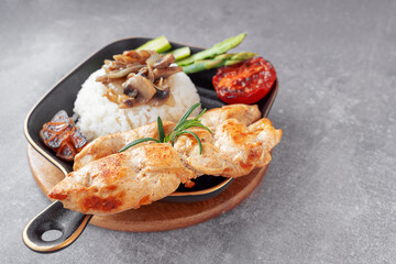 Grilled chicken kebabs with rice, fried mushrooms and vegetables, served on a black plate in a cosy setting