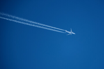 Airplane in the blue sky with contrail