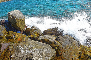 Scogli con mare mosso e spruzzi.