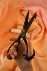 Scissors of thread peach and yellow color on a peach and pink background