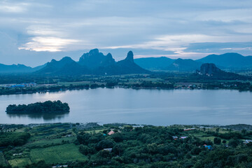 Phusab Lek : LOPBURI, THAILAND, Tranquil Waterscape: A serene panorama unfolds, featuring a tranquil lake embraced by rolling hills and under a gentle, clouded sky. 