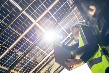 Engineer in safety vest and helmet pointing towards a solar powered carport, illustrating eco-friendly innovation in parking infrastructure. Solar panels provide shade and sustainable energy.