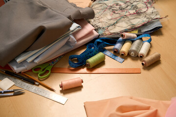 In sewing workshop. Textile, thread, sciccors, pattern on wood background top view