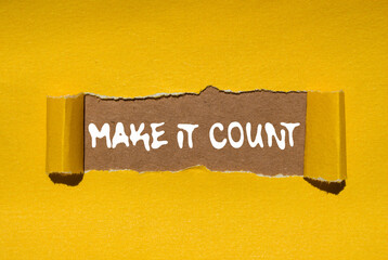 Make it count message written on ripped torn yellow paper on brown background. Conceptual make it...