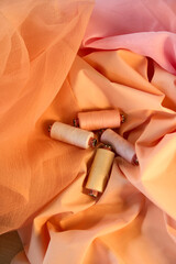 Spools of thread peach and yellow color on a peach and pink background