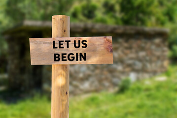 Let us begin message written on wooden sign on nature background. Conceptual let us begin symbol. Copy space.