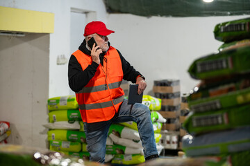 An older worker in a pet food warehouse prepares deliveries of goods for pet stores.