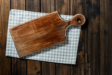 Empty cutting board over towel on wooden kitchen table, top view, closeup, copy space