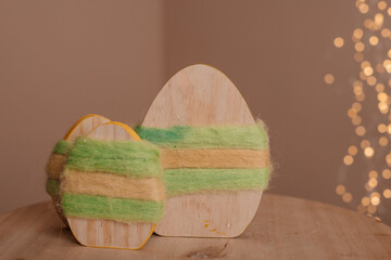 A wooden Easter egg wrapped in green ribbon, illuminated by warm fairy lights.