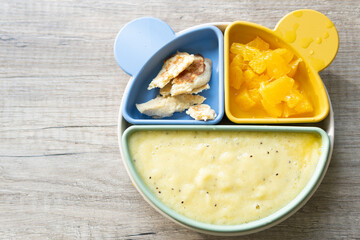infant and child feeding, nutritious plate with orange fruit puree and oatmeal pancakes. on table with copy space studio photo.