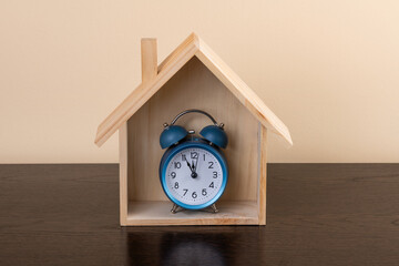 Symbolic wooden house and alarm clock
