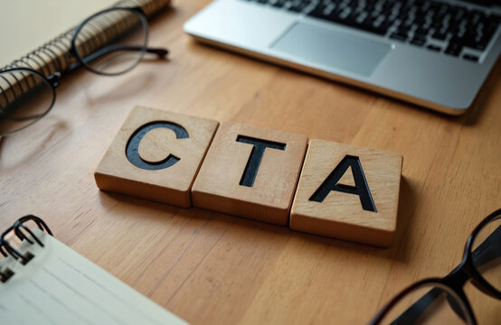 Wooden cubes spell CTA abbreviation. Laptop, glasses, notebook on wooden table. Digital marketing, online business, web design, advertising concept. Call to action.