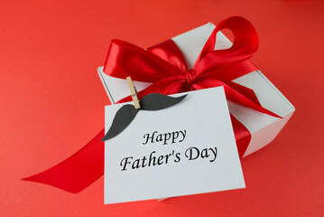 Happy Father's Day. Gift box with red bow and accessories on red background. Card, banner, layout for Father's Day.