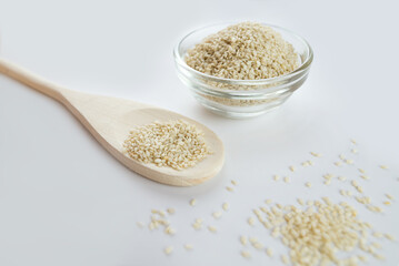 Sesame bowl on a white background. Sesame seeds in a wooden spoon, isolated on a white