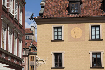 Decorative sundial on a building wall in Warsaw, blending history with functional design.