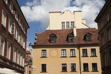 Decorative sundial on a building wall in Warsaw, blending history with functional design.