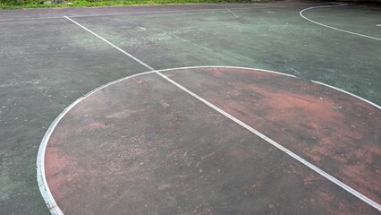 dirty worn basketball court with acrylic asphalt concrete surface at night