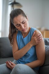 Fototapeta premium Close up of tired young woman displaying discomfort and frustration in her living room during the day