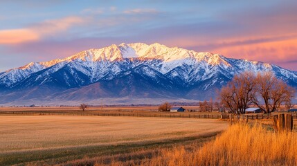 Fototapeta premium Majestic snow-capped mountain at sunset, with vibrant skies and serene fields in foreground