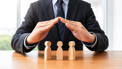 Man's hands protect family figures. Concept of family care, support, community, and social responsibility offering shelter and defense.