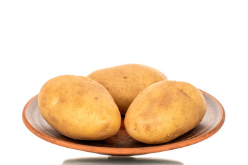 Several unpeeled raw potatoes on a clay plate isolated on a white background, close-up.