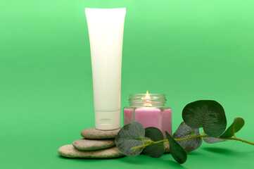 Scented candle, white tube, stones, green eucalyptus branch.
