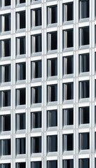 A modern building facade featuring a grid of windows, showcasing a sleek and geometric design with a focus on symmetry and architectural detail.