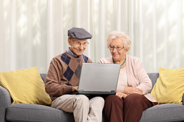 Elderly couple sitting on a sofa and using a laptop