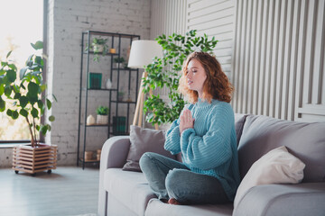 Young woman meditating in cozy living room setting, showcasing relaxation and mindfulness
