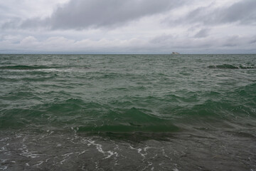 An incoming wave on the Black Sea and a pebble beach on the Sochi coast on a summer day with clouds, Sochi, Krasnodar Territory, Russia
