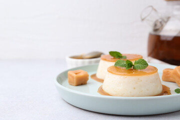 Tasty puddings with caramel sauce served on white table, closeup. Space for text