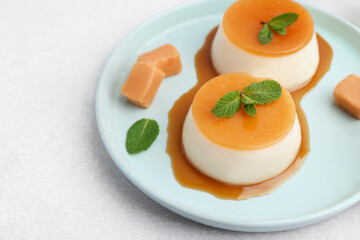Tasty puddings with caramel sauce served on white table, closeup. Space for text