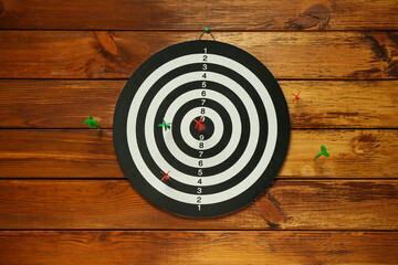 Dart board with colorful arrows on wooden background