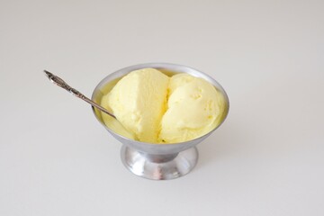 Enjoy creamy yellow banana ice cream in a stylish metal bowl with a spoon for a delightful treat