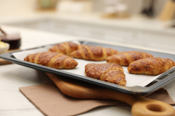 Freshly baked croissants on light table indoors, closeup