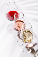 Three wine glasses filled with red, white, and rose wine