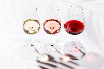 Three wine glasses filled with red, white, and rose wine
