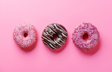 A colorful assortment of vibrant donuts with various toppings arranged on a pink