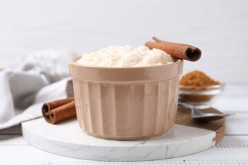 Tasty rice pudding with cinnamon served on white wooden table, closeup