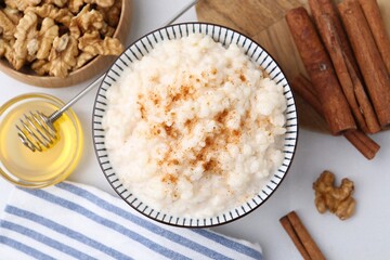 Tasty rice pudding with cinnamon served on white table, flat lay